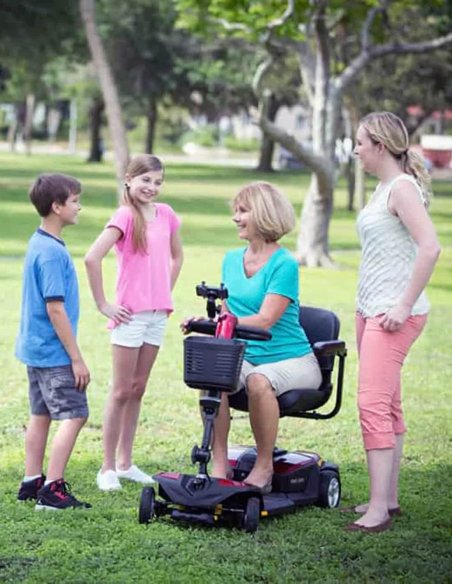Femme en scooter PMR Pride Endurance LI avec sa famille dans un parc
